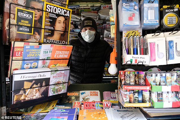 Pictured: A newspaper stand worker wearing a protective mask is seen after Italy tightened the lockdown measures to combat the novel coronavirus