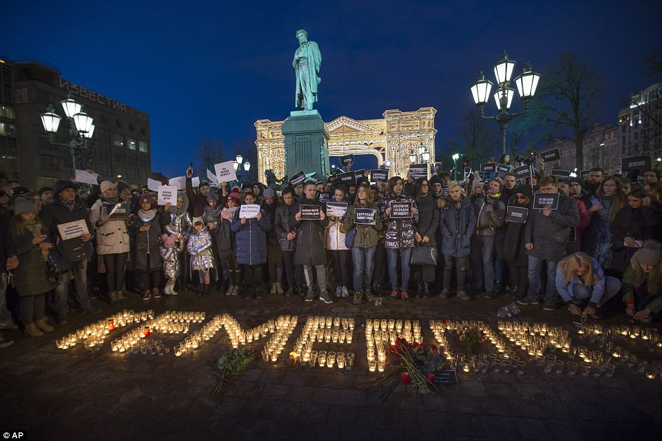People stand in front of the word Kemerovo, made up of candles, to commemorate the victims of Sunday
