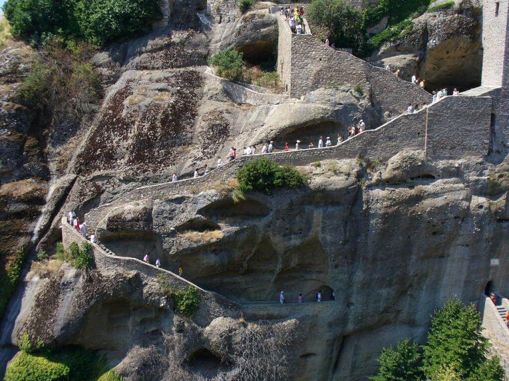 Туристы поднимаются по ступеням с скалах к монастырю Ступени в скалах